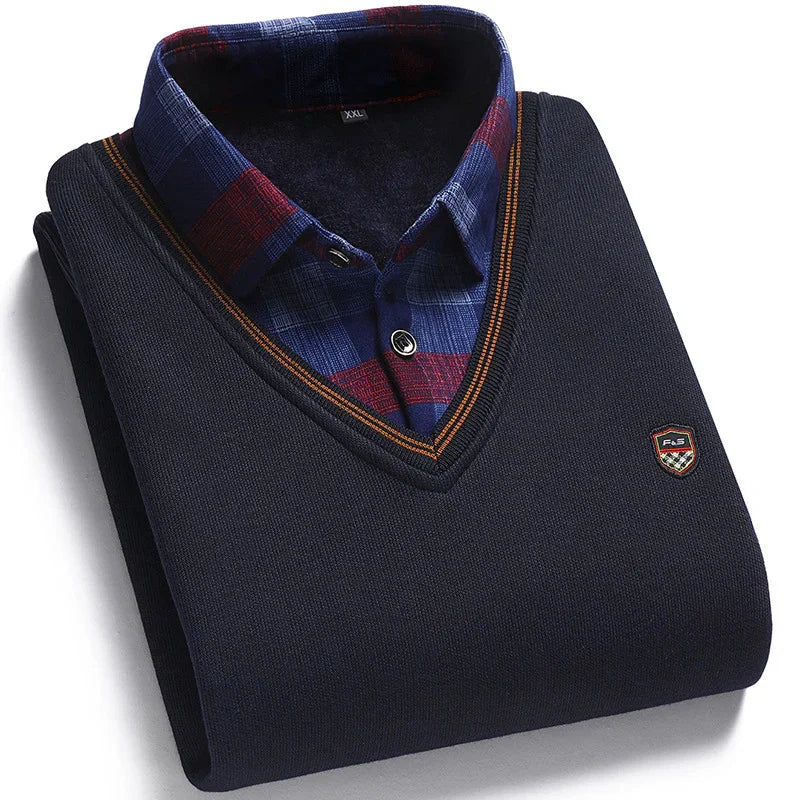 Folded navy blue V-neck sweater with orange trim over a blue and red plaid button-up shirt