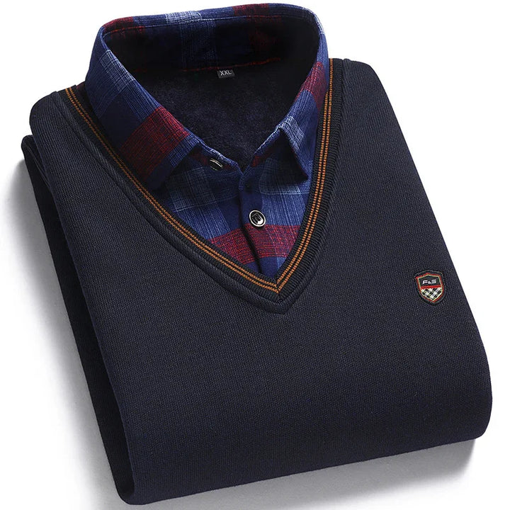 Folded navy blue V-neck sweater with orange trim over a blue and red plaid button-up shirt