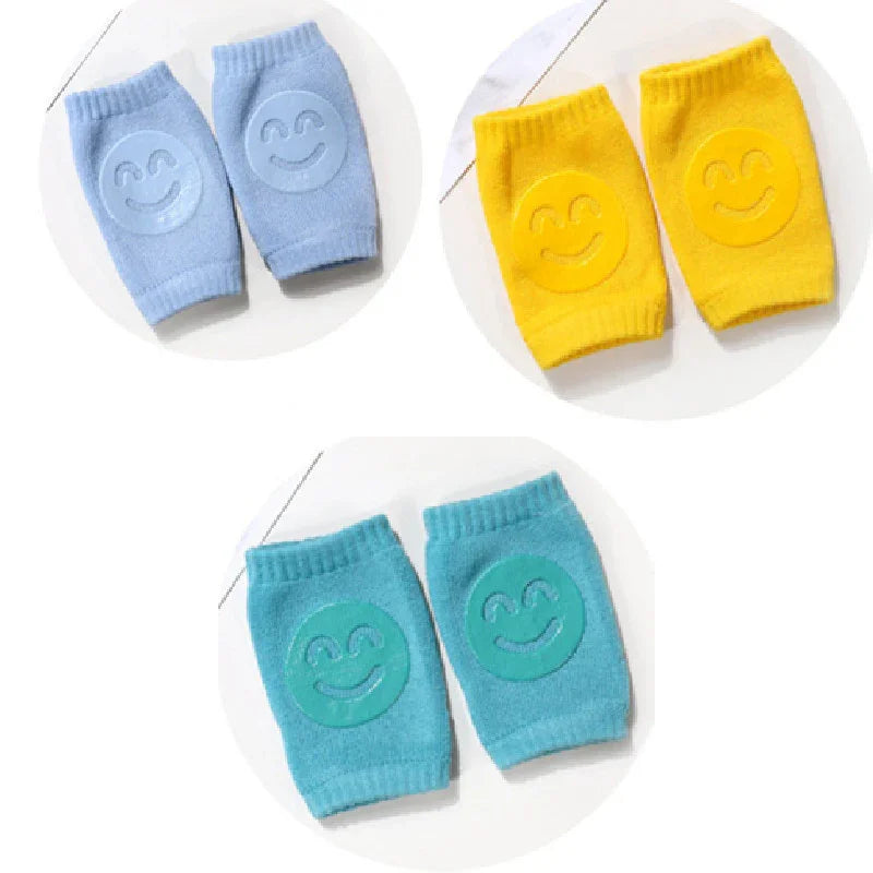 Three pairs of colorful knee pads with smiling face designs in blue, yellow, and teal on white background