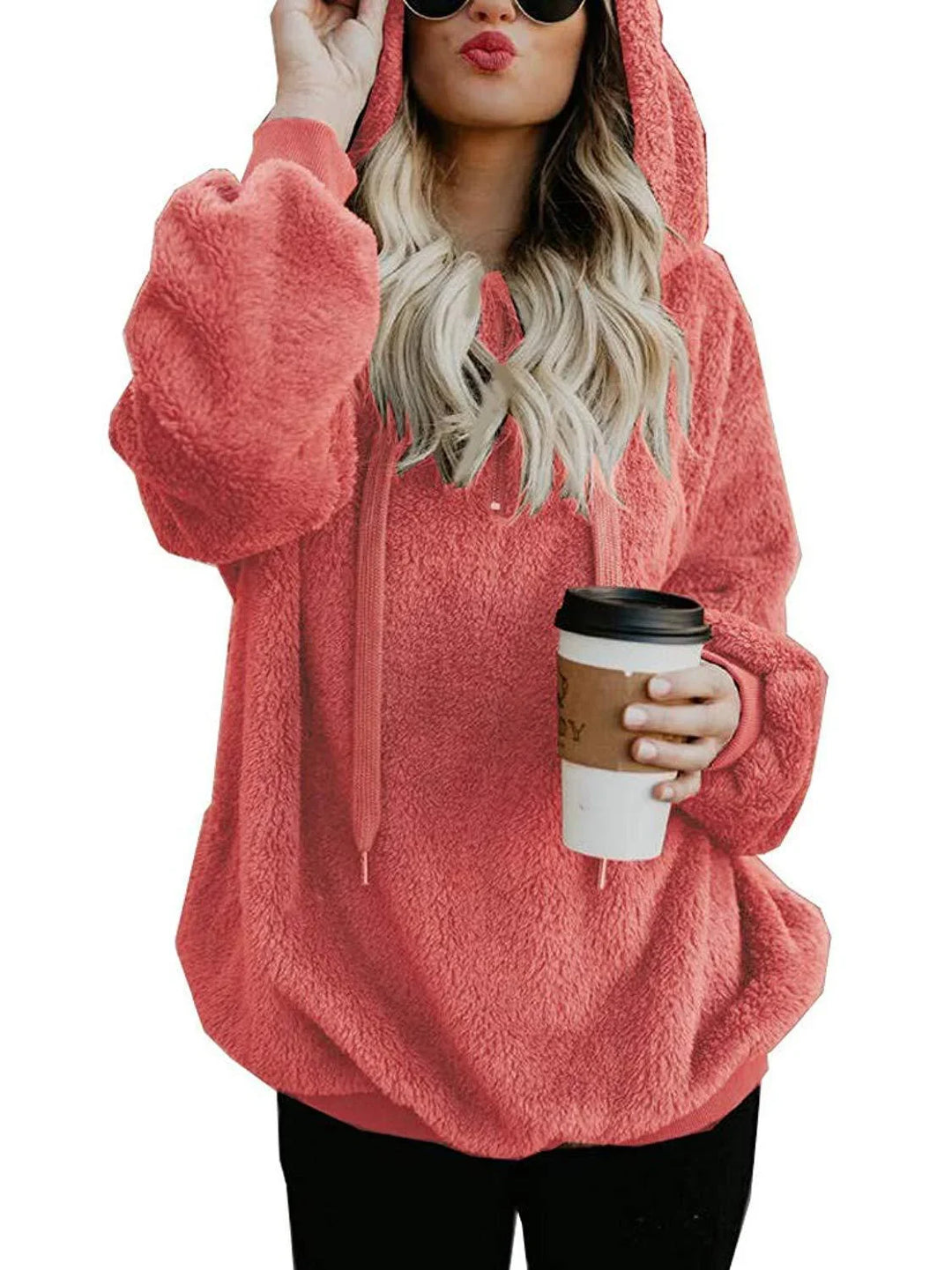 woman wearing coral pink fluffy hooded sweatshirt holding takeaway coffee cup