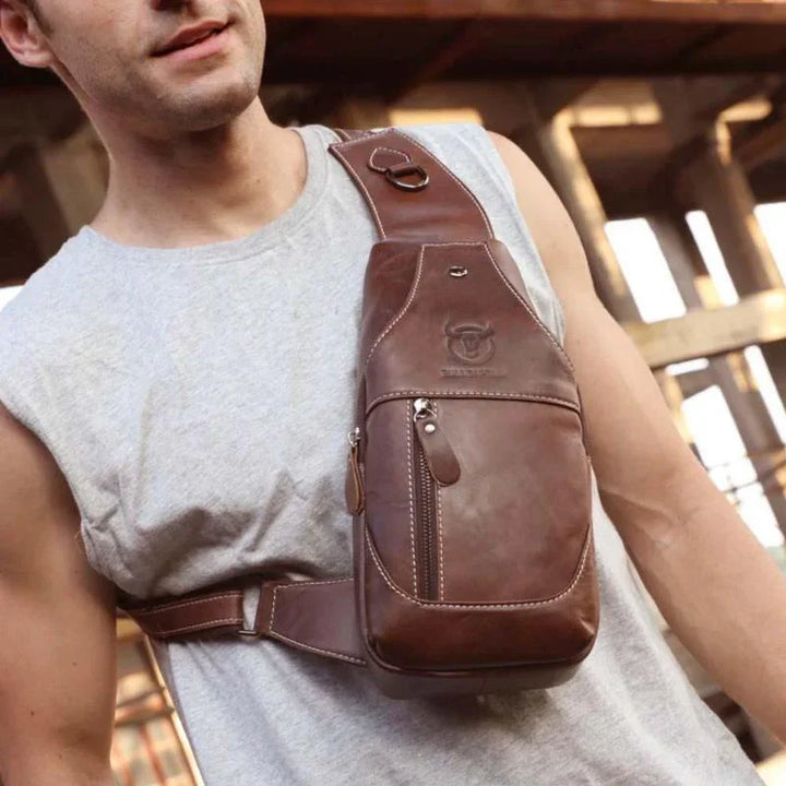 Man wearing brown leather crossbody sling bag with zippered pocket and embossed logo