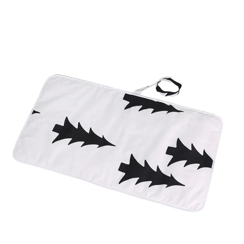 White fabric changing mat with black leaf patterns and attached matching strap