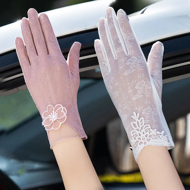 Pair of pink and white lace gloves with floral embroidery worn outdoors on hands