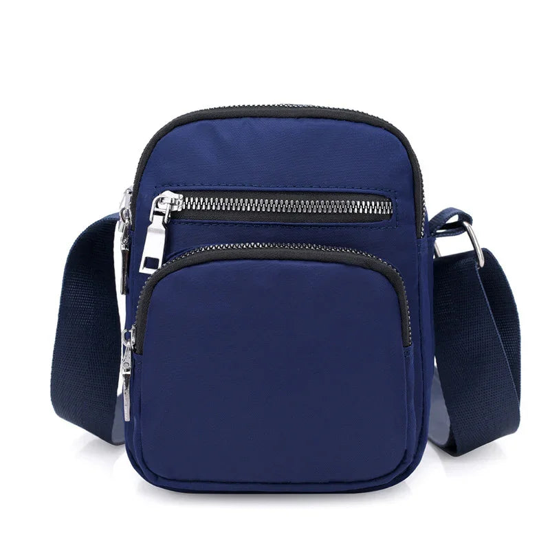 Compact navy blue crossbody bag with adjustable strap and silver zippered pockets