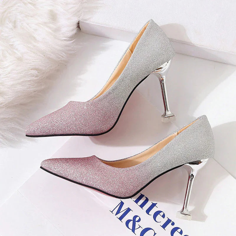 Pair of glittery pink and silver high heel pumps with metallic stiletto heels on white surface