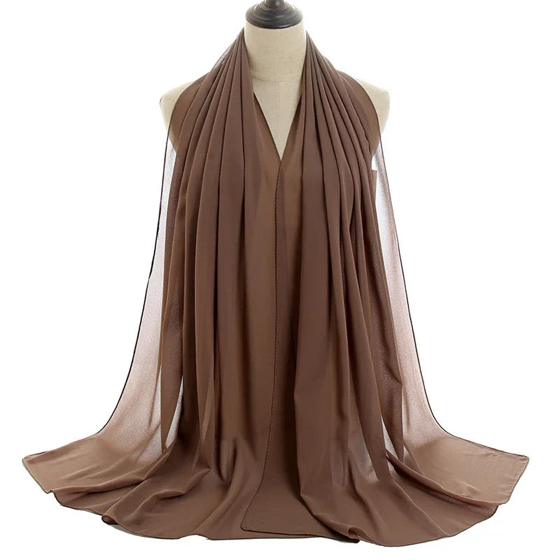 Elegant brown chiffon scarf draped on beige mannequin with soft folds and sheer texture