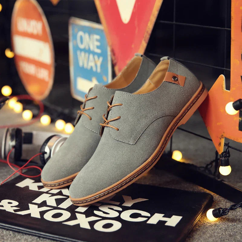 Gray suede casual shoes with brown laces and sole displayed with street signs and string lights