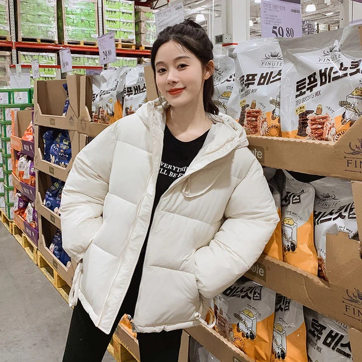Young woman in white puffer jacket posing in a grocery store aisle with snack products on shelves