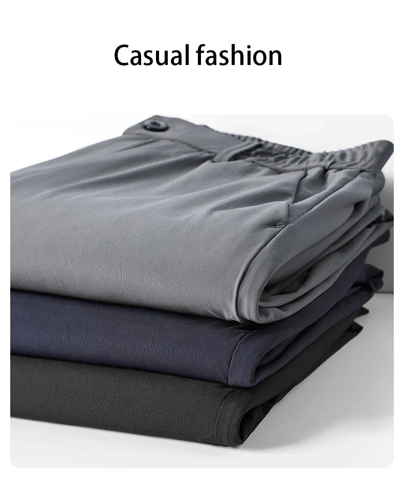 Stack of folded casual pants in gray, navy, and black with elastic waistbands
