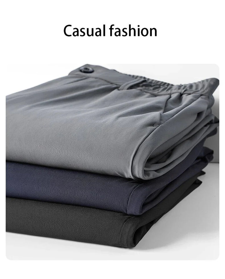 Stack of folded casual pants in gray, navy, and black with elastic waistbands