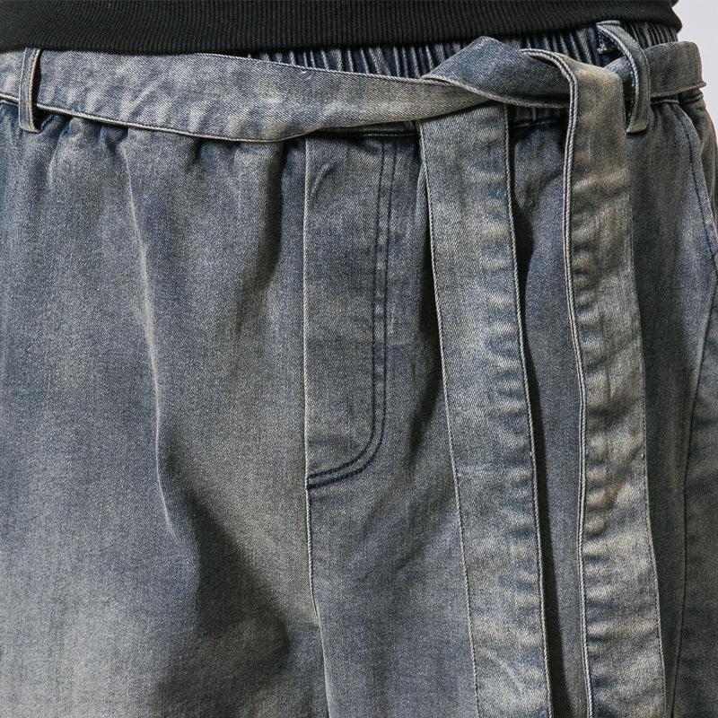 Close-up of grey denim pants with elastic waistband and matching denim belt