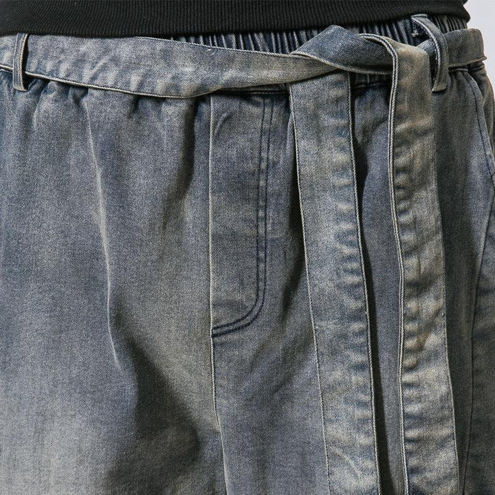 Close-up of grey denim pants with elastic waistband and matching denim belt