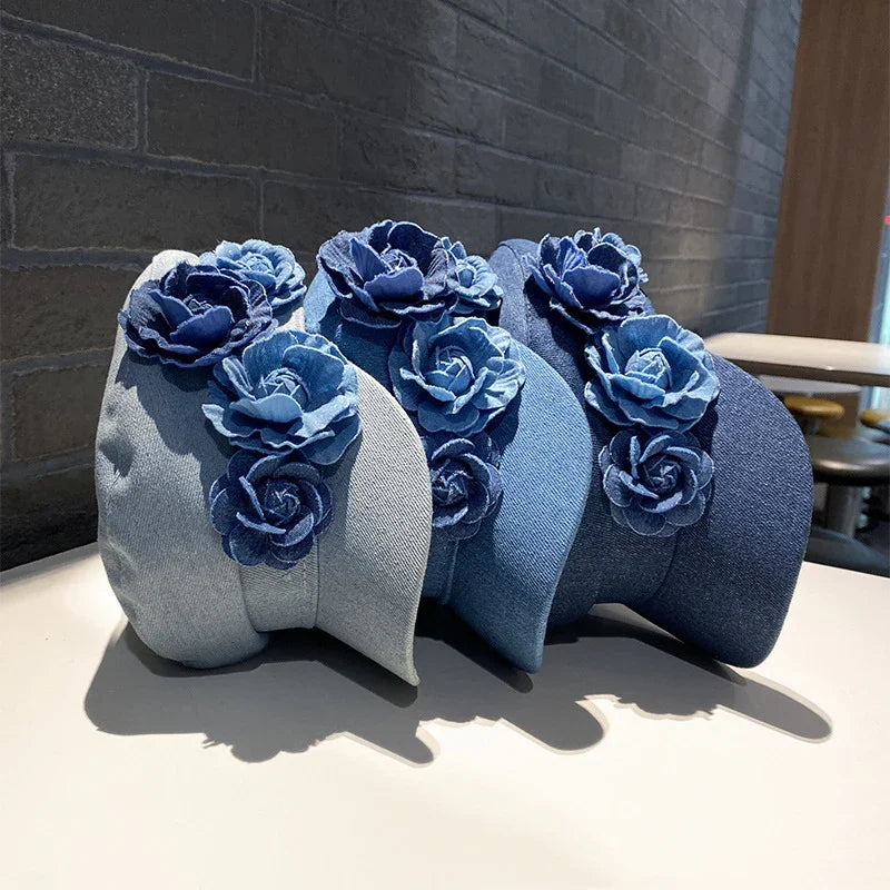 Set of denim baseball caps in light to dark blue with blue denim flower decorations on a white table