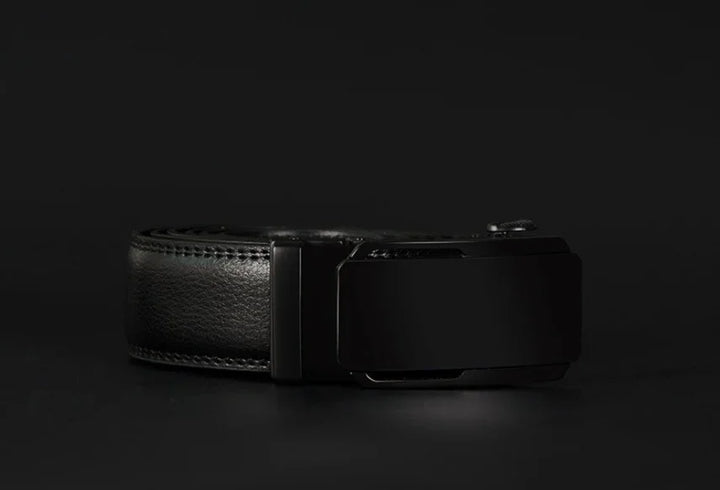 Close-up of a black leather belt with a matte black buckle on a dark background