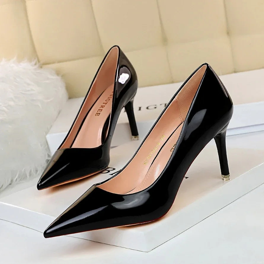 Elegant black patent leather pointed-toe high heel pumps on white box