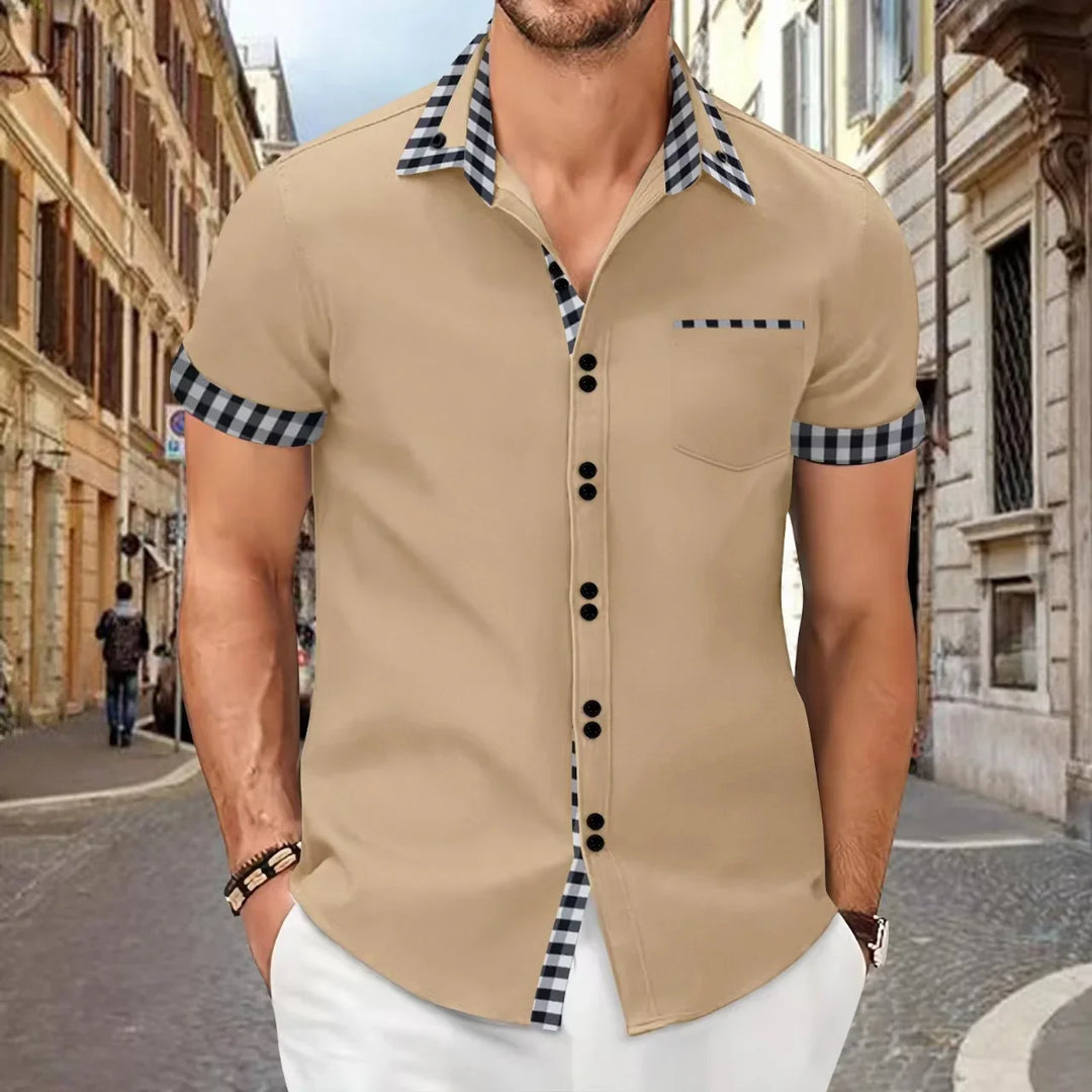Man wearing beige short-sleeve shirt with black and white checkered collar and cuffs on city street