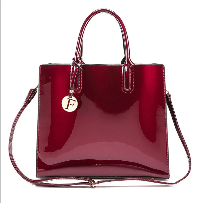 Shiny burgundy patent leather tote bag with top handles, detachable shoulder strap, and circular F charm