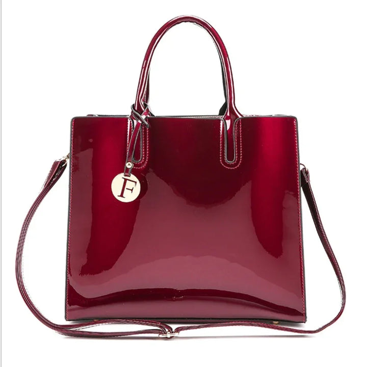 Shiny burgundy patent leather tote bag with top handles, detachable shoulder strap, and circular F charm