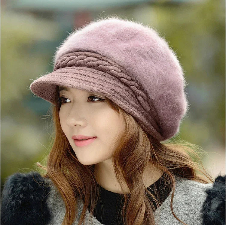 Woman wearing a soft pink wool beret with braided detail and a short brim, styled with wavy hair