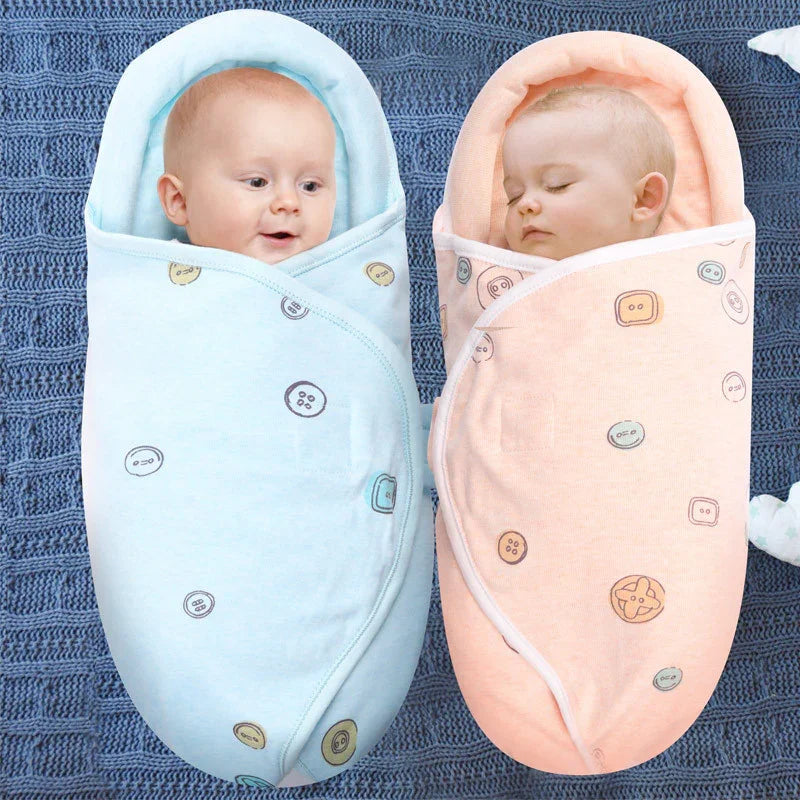 Two babies swaddled in pastel blue and pink button-print blankets on a knitted blue blanket