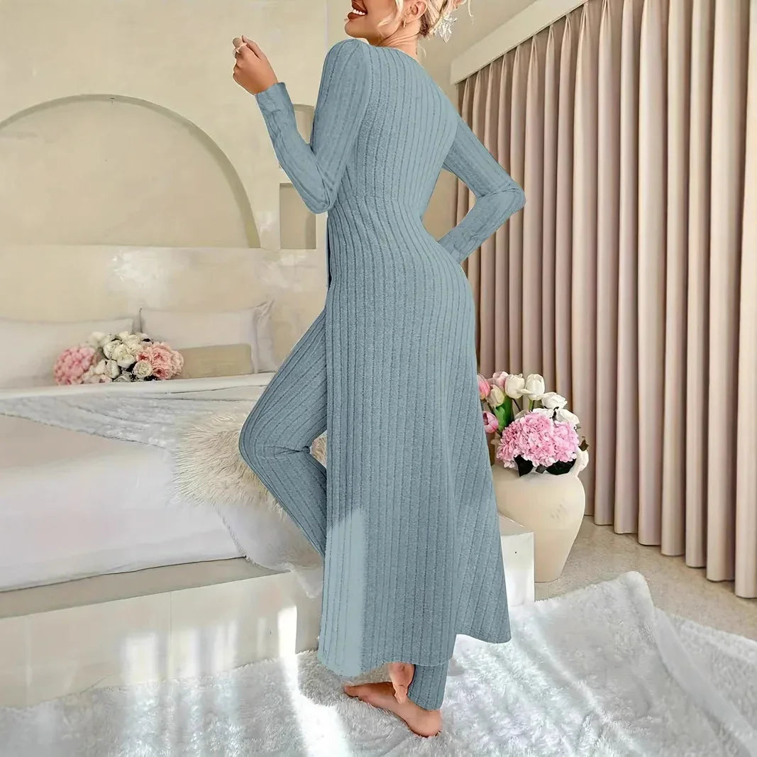 Woman in light blue ribbed knit long cardigan and matching pants in cozy bedroom with flowers