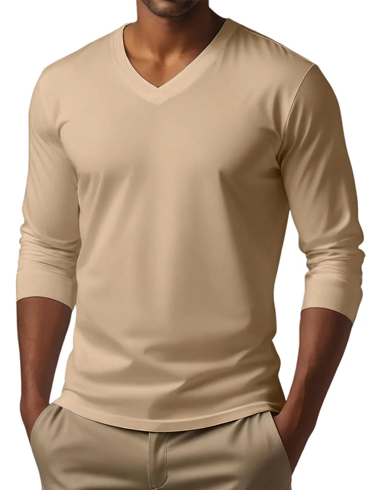 Man wearing beige V-neck long sleeve shirt and matching beige pants with hands in pockets