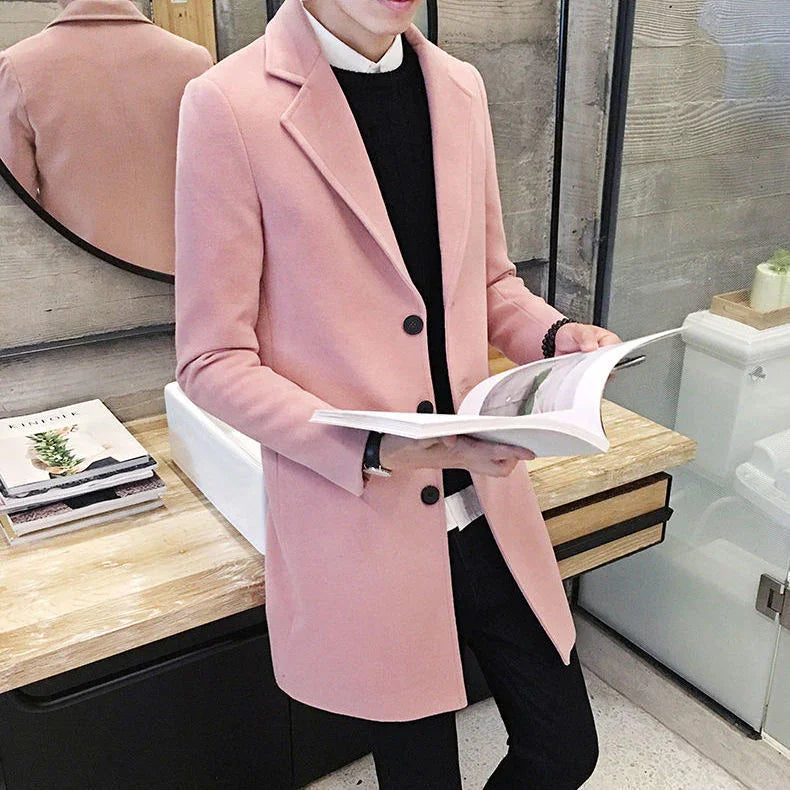 Man wearing stylish pink overcoat and black sweater reading a book indoors with modern decor
