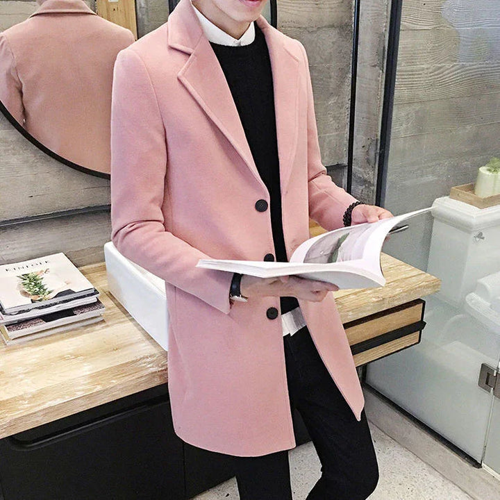 Man wearing stylish pink overcoat and black sweater reading a book indoors with modern decor