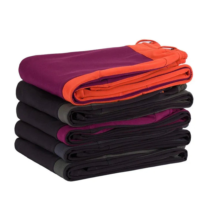 Stack of folded athletic leggings in black, purple, and orange colors with contrasting waistbands