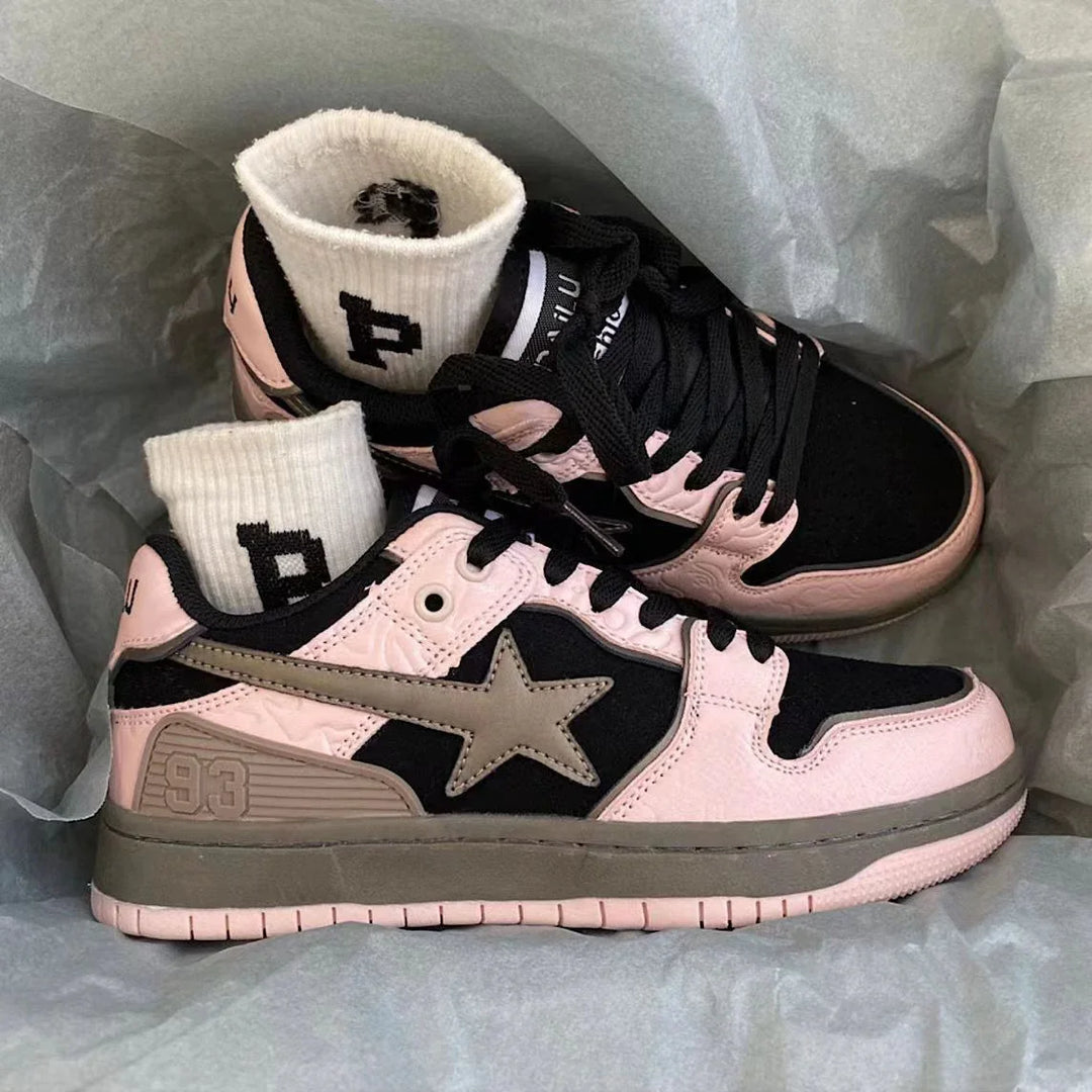 Pair of black and pink Bape sneakers with star logo and white socks inside a box