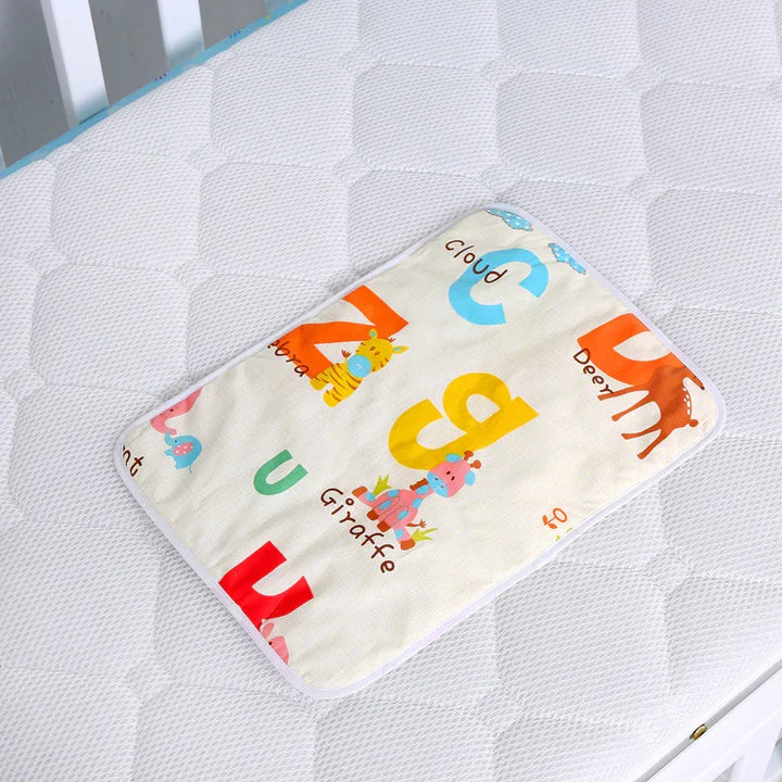 Colorful baby changing pad with animal alphabet print on white quilted crib mattress