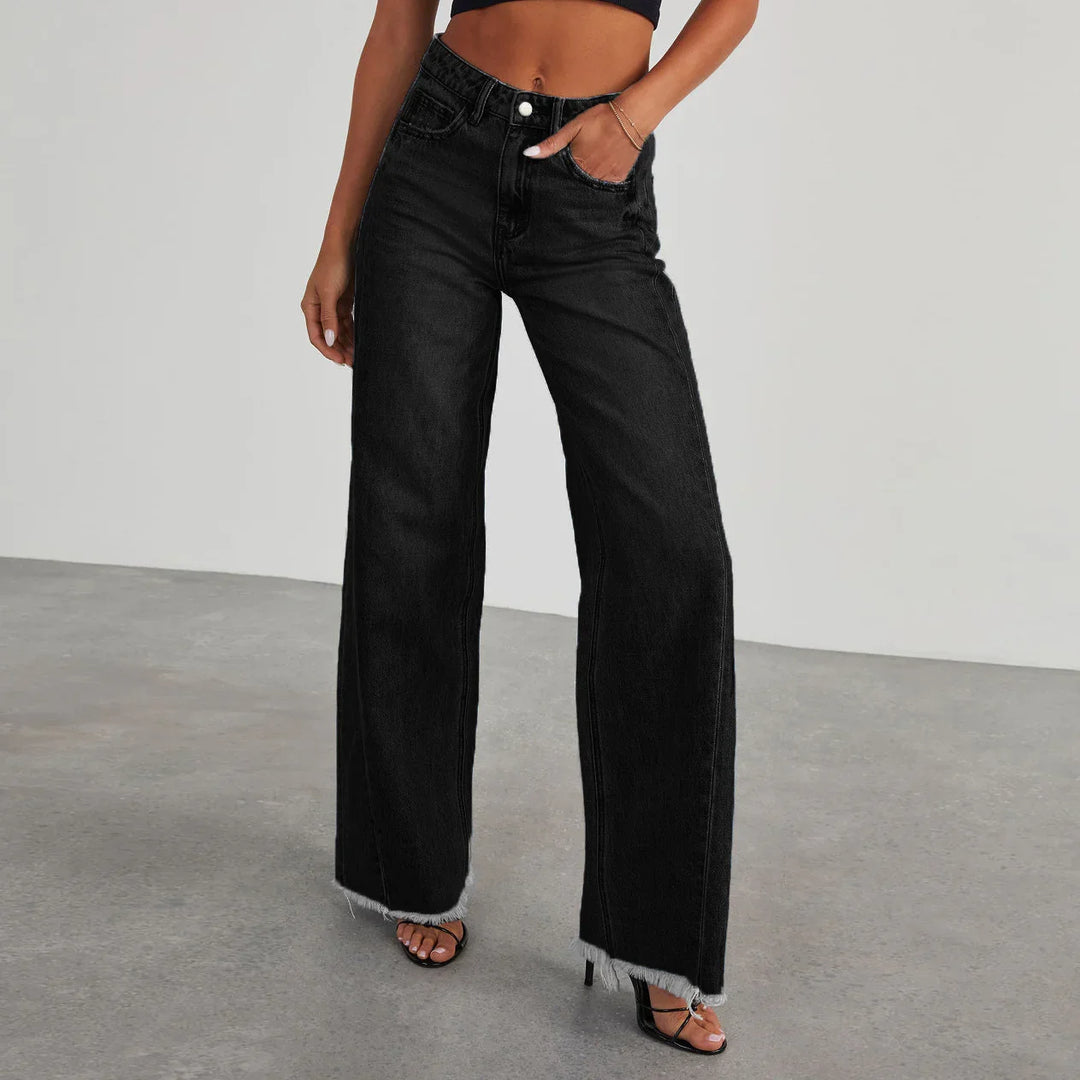 Woman wearing high-waisted black wide-leg jeans with frayed hems and black heeled sandals