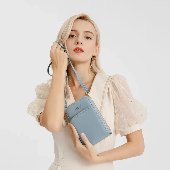 Blonde woman in cream dress holding light blue crossbody pouch bag with wrist strap on white background