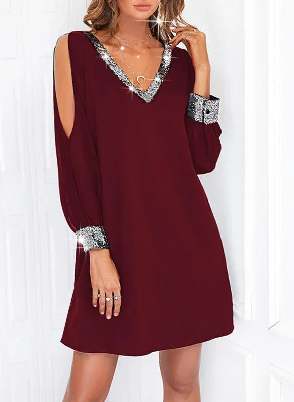 Woman wearing burgundy V-neck dress with silver sequin trim and cut-out sleeves in bright setting