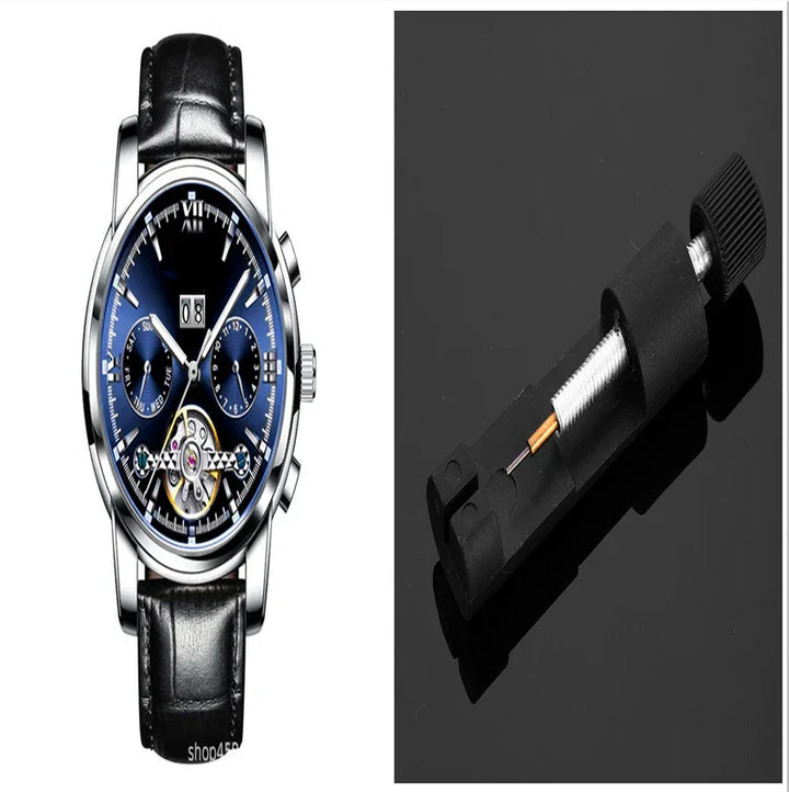 Luxury mechanical wristwatch with black leather strap next to a watch spring bar tool on black surface