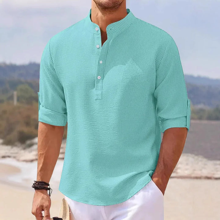 Man wearing light blue casual waffle-knit mandarin collar shirt with rolled-up sleeves at the beach