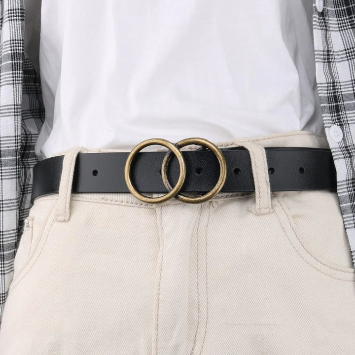 Black leather belt with double brass ring buckle worn with beige pants and white shirt