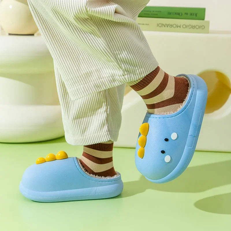 Child wearing blue dinosaur slippers with yellow spikes and brown striped socks indoors