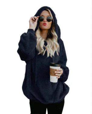 Woman in oversized black hooded fleece sweater wearing sunglasses and holding a takeaway coffee cup