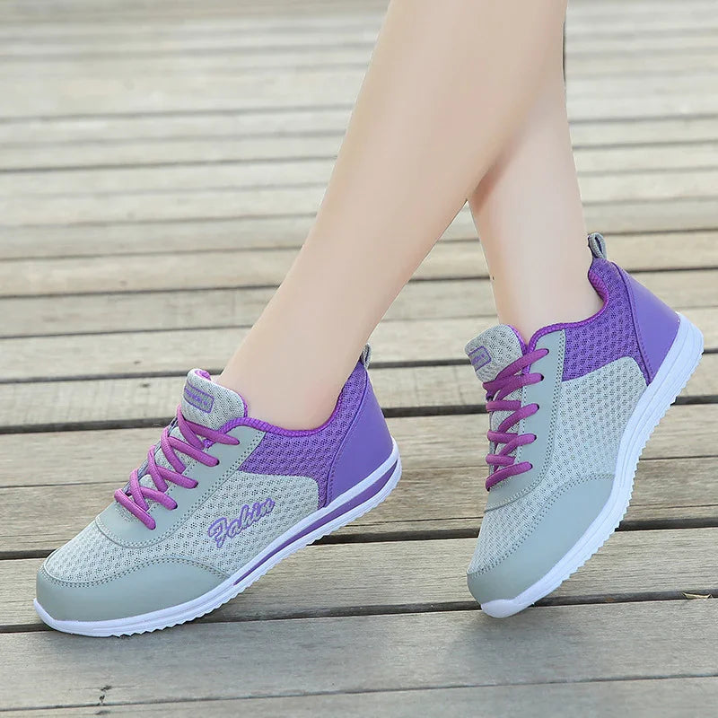 Light gray and purple lightweight breathable sneakers with pink laces on wooden deck