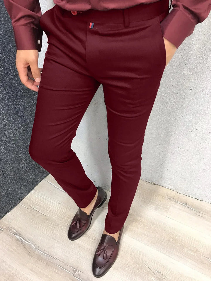 Men's slim-fit burgundy dress pants paired with matching shirt and brown leather tassel loafers