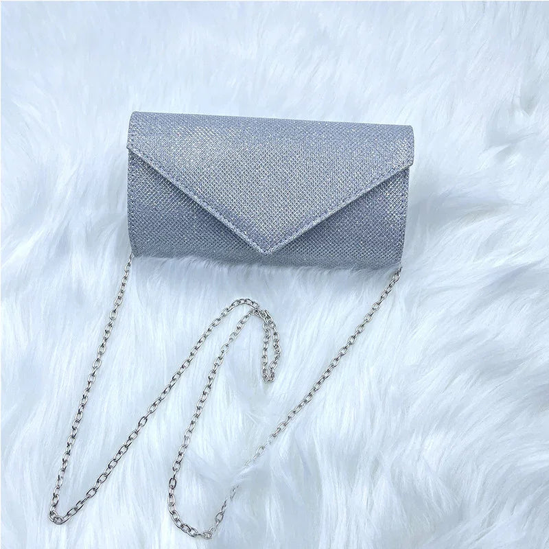 Silver glitter clutch purse with chain strap on white faux fur background