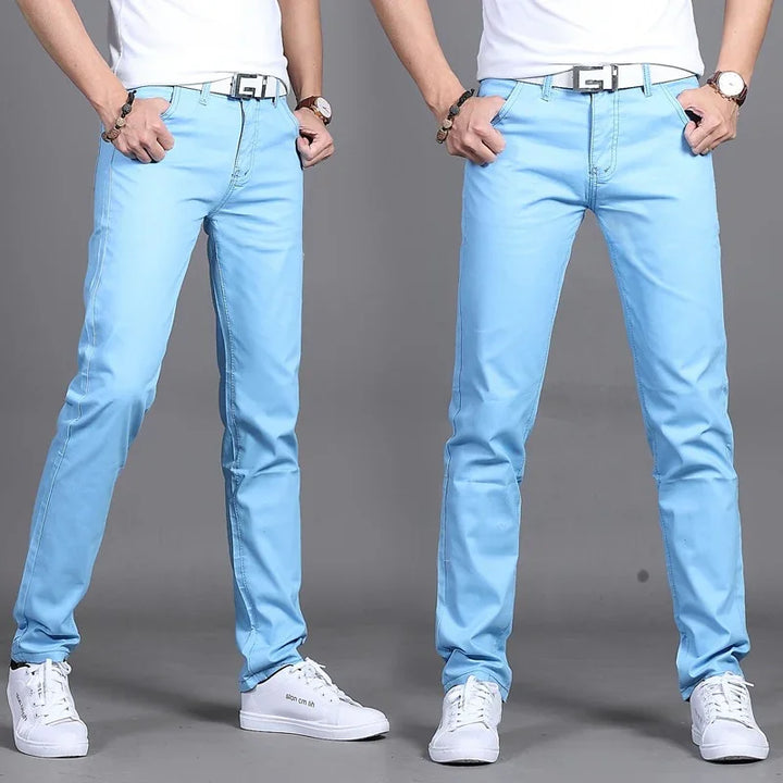 Men's slim fit light blue jeans paired with white belt and white sneakers on gray background
