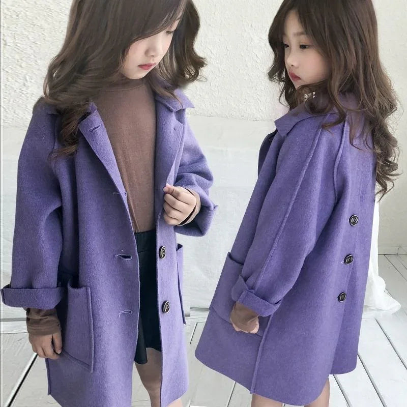 Young girl wearing a stylish purple wool coat with large buttons and rolled sleeves indoors