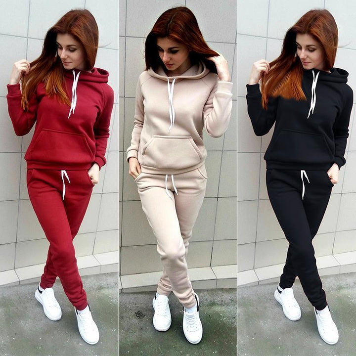 Woman modeling casual hooded sweatshirt and jogger pants sets in red, beige, and black with white sneakers against tiled wall
