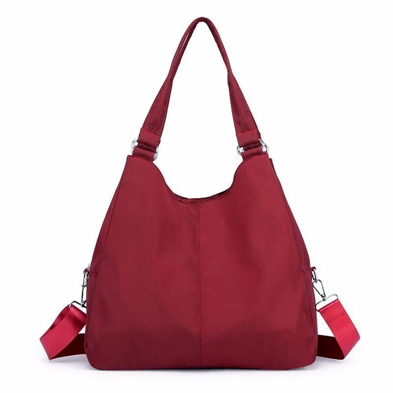 Maroon tote handbag with double handles and detachable shoulder strap on white background