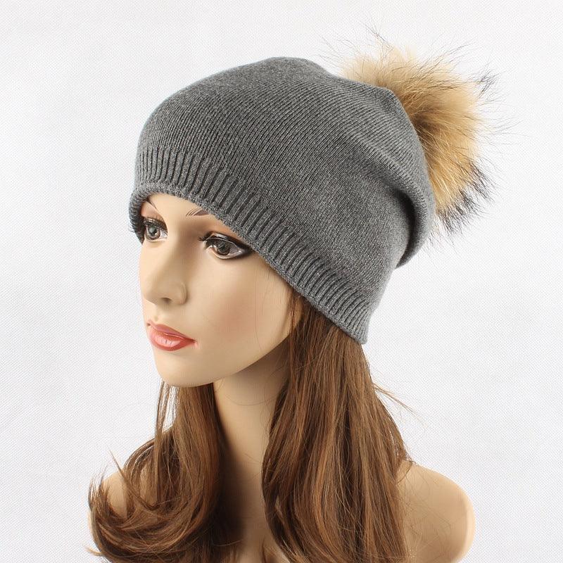 Gray knit beanie hat with beige fur pompom on mannequin head with long brown hair