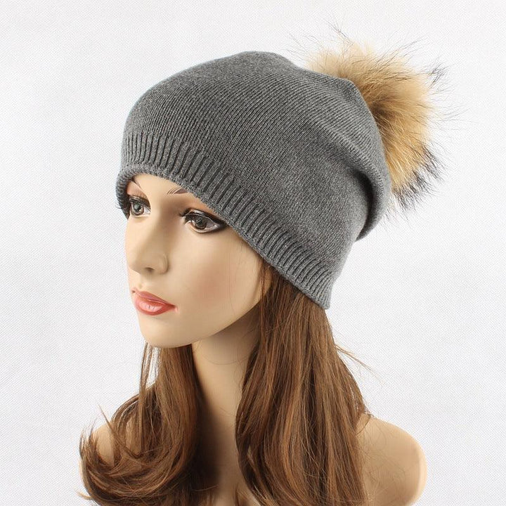 Gray knit beanie hat with beige fur pompom on mannequin head with long brown hair