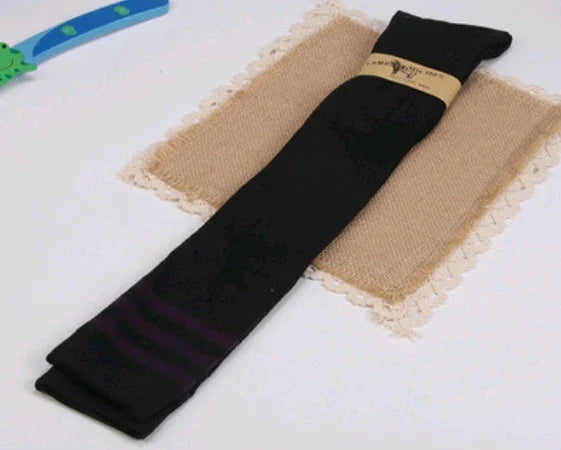 Black folded socks with purple stripes on a beige burlap mat with lace edges, white background