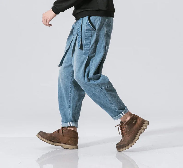 Casual blue denim pants with rolled cuffs and brown leather boots on a walking person